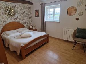 a bedroom with a bed and a chair and a window at Le Logis de la Lande in La Boissière-des-Landes