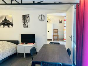 ein Zimmer mit einem Bett und einem Schreibtisch mit einem Fernseher in der Unterkunft Le Bon Repos - Séjours professionnels et vacances en famille aux portes de Paris in Garches