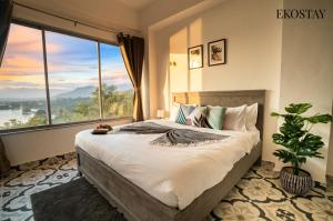 a bedroom with a large bed with a large window at EKOSTAY - Eternal Wave in Lonavala +23 photos