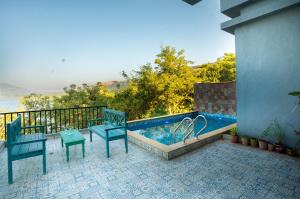 a swimming pool on a balcony with two blue chairs at EKOSTAY - Eternal Wave in Lonavala