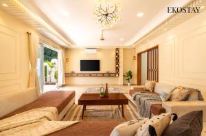 Una sala de estar con un sofá y un televisor. en EKOSTAY - Azure Villa, en Lonavala