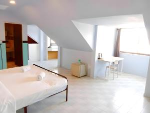a white room with a bed and a table at XX Mitr Inn - Phuket Old Town in Phuket