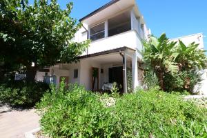 a white house with trees in front of it at Residence Oasis Punta Prosciutto in Punta Prosciutto