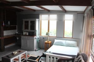 a bedroom with a bed and a table and windows at Next Chapter in Great Brak River