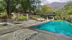 a swimming pool with chairs and a gazebo at Ambady Estate in Munnar
