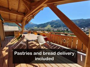 a wooden deck with a table and chairs on a balcony at Résidence Julianna , trajets remontées mécaniques , livraison viennoiseries, piscine couverte in Morzine +124 photos