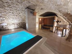 a swimming pool in a room with a stone wall at Au Ralenti du Lierre in Beaumettes