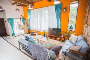 a living room with orange walls and blue couches at Hill Atagawa Villent in Higashiizu