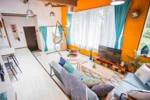 a living room with a couch and a tv at Hill Atagawa Villent in Higashiizu