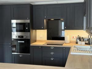 a kitchen with black cabinets and stainless steel appliances at Sea Views Oddfellows in Pakefield