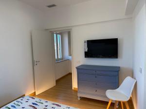 a bedroom with a tv and a blue dresser with a white chair at Blu Celeste in Porto Santo Stefano
