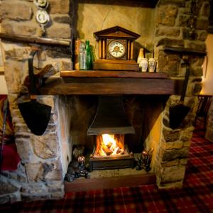 a stone fireplace with a clock on top of it at The Pheasant Inn in Falstone