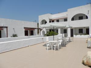 a patio with white chairs and tables and a building at Aeolos Hotel Apartments in Gythio