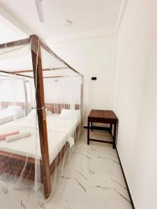 a bedroom with two beds and a table at Garden Beach Hotel in Arugam Bay