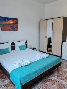 a bedroom with a large bed with a blue bedspread at Къща за гости Пиргос in Burgas City