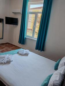 a bedroom with a bed with blue curtains and a window at Къща за гости Пиргос in Burgas +43 photos