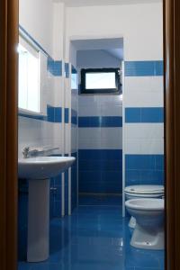 a blue and white bathroom with a sink and a toilet at Residence Oasis Punta Prosciutto in Punta Prosciutto +28 photos