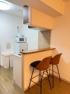a kitchen with two chairs sitting at a counter at Camelot House in Fukuoka