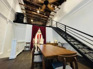 a dining room with a wooden table and a staircase at 1917 By MUO in Muar