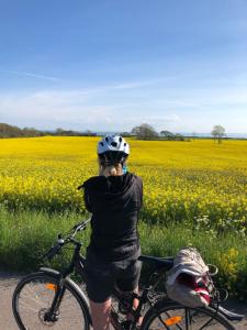 a woman riding a bike in front of a field at Cozy cottage by the sea, near Kullaberg in Farhult