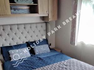 a bed with blue sheets and pillows in a bedroom at Valeria - Gold 3 bedroom with Garden and Parking - Seal Bay in Selsey +17 photos