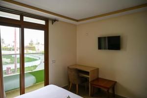 a room with a desk and a tv on the wall at Hôtel Jawharat El Jadida in El Jadida