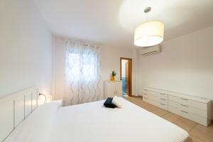 ein weißes Schlafzimmer mit einem weißen Bett und einer Lampe in der Unterkunft Dúplex La Casilla in San José