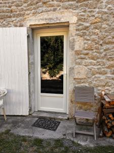 a door to a stone building with a chair next to it at Chez Amélie chambre-location in Saint-Germain-dʼEsteuil