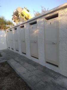 una fila de puestos blancos en una pared en Casette sulla spiaggia di Punta Prosciutto, en Punta Prosciutto