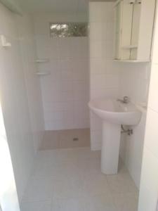 Un baño blanco con lavabo e inodoro. en Casette sulla spiaggia di Punta Prosciutto, en Punta Prosciutto