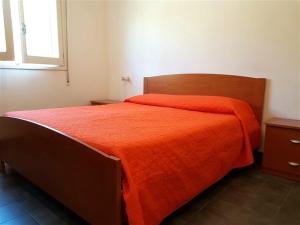 Un dormitorio con una cama con una manta naranja. en Casette sulla spiaggia di Punta Prosciutto, en Punta Prosciutto