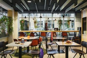 un restaurant avec des tables et des chaises et une voiture à l'extérieur dans l'établissement Moxy Paris Bastille, à Paris
