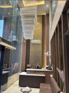 Ein Mann, der an einem Schreibtisch in der Lobby sitzt. in der Unterkunft Hotel Tarun Palace, Bhopal in Bhopal