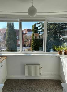 a living room with three windows and a radiator at Kleiters Bed & Kitchen in Copenhagen