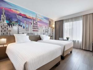 バンコクにあるノボテル バンコク オン サイアム スクエアの絵画のあるホテルの部屋にはベッドが2つある