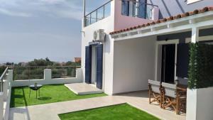 VotsalákiaにあるKamara Luxury ground floor apartmentsの白い家(緑の芝生のあるバルコニー付)