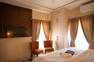 een slaapkamer met een bed en 2 stoelen en een televisie bij Just Move Premium 2BR Suite, Near ISB Int'l AIRPT in Islamabad +29 foto's
