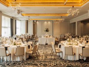 a banquet room with white tables and chairs and chandeliers at The Playford Adelaide - MGallery in Adelaide +37 photos