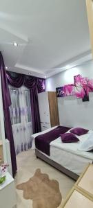 - une chambre avec un grand lit et des oreillers violets dans l'établissement Goga Makharadze, à Batoumi