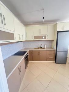 Una cocina con gabinetes blancos y un refrigerador de acero inoxidable. en Andria Apartment, en Sarandë