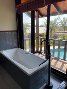 eine Badewanne in einem Raum mit einem großen Fenster in der Unterkunft Dalasone Pool Villa with Stunning Mountain View in Vang Vieng