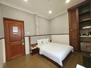 Un dormitorio con una cama blanca y una puerta de madera. en Văn Hoa Hotel, en Ho Chi Minh