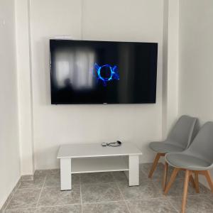 a tv on a wall with a white table and two chairs at villa 58 coral bay seafront in Peyia