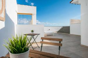 a balcony with a wooden bench and a table at APARTAMENTOS CARMEN in Maro