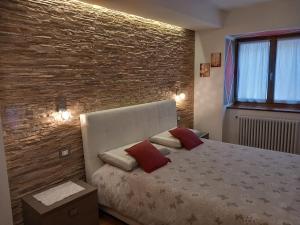 a bedroom with a bed and a brick wall at Appartamenti Lucia in Andalo