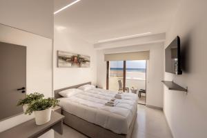 a white bedroom with a bed and a view of the ocean at SEVIS SUITES in Ayia Napa