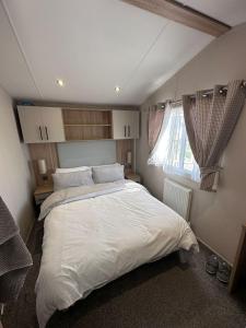une chambre avec un grand lit blanc et une fenêtre dans l'établissement Caravan Selsey, à Selsey