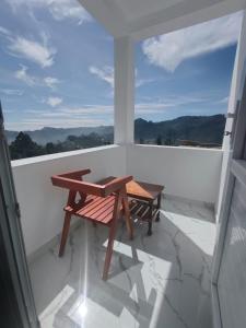 una mesa de madera y un banco en un balcón en THE DEW stay, en Kodaikanal