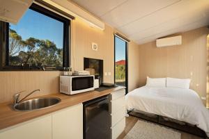 a kitchen with a bed and a microwave and a sink at Rowsley Valley Tiny House 2 by Tiny Away in Ingliston