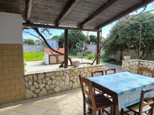 a table and chairs on a patio with a stone wall at ViLLA GASPARE FRONTE MARE in Favignana